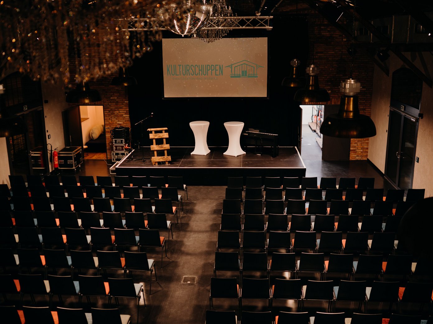 Veranstaltungsbestuhlung von oben fotografiert, Leinwand mit Schriftzug "Kulturschuppen" im Hintergrund