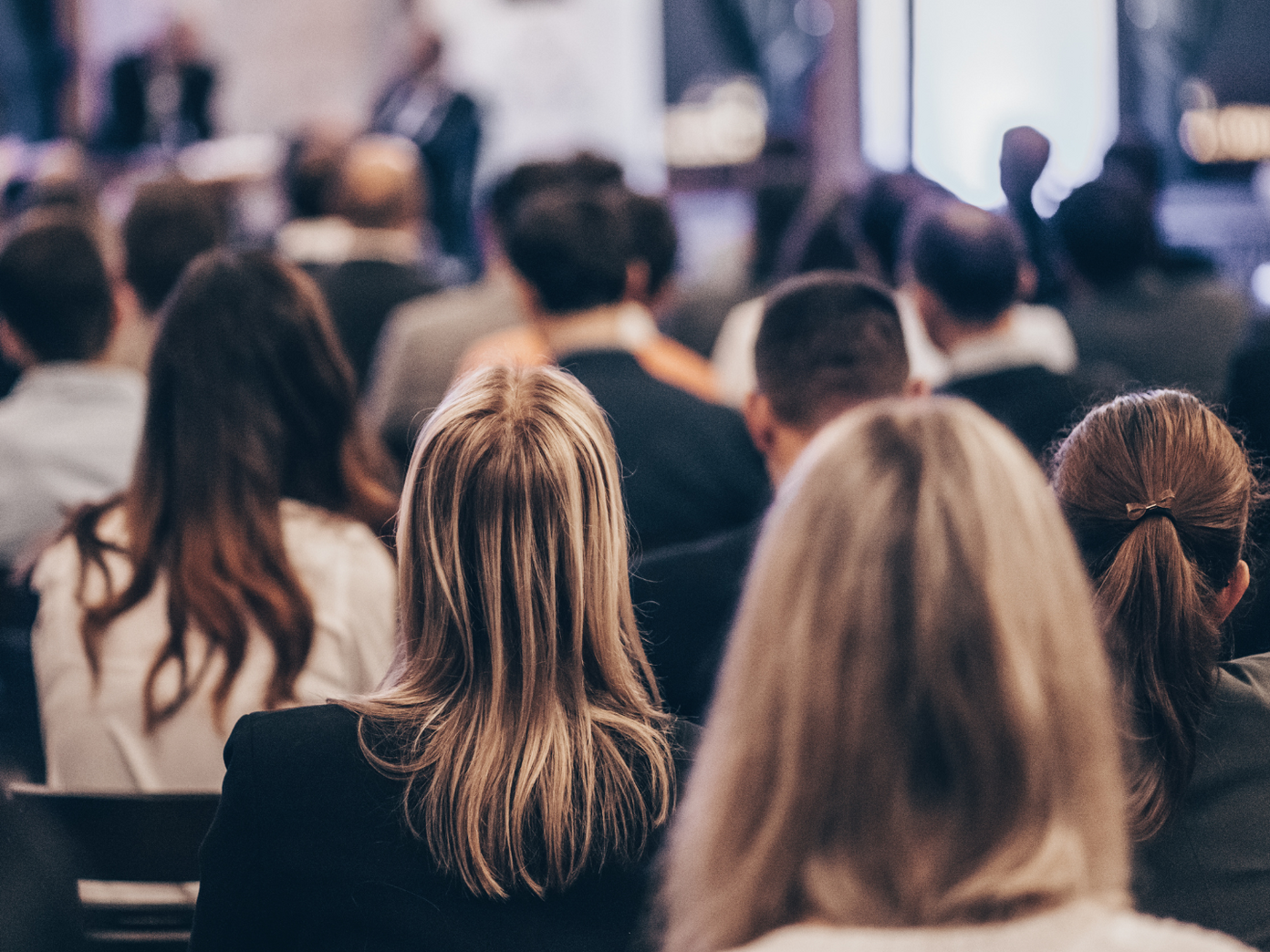 Tagungen Hinterköpfe von sitzenden Menschen die auf eine Bühne schauen